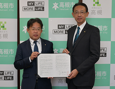 協定書を手にする谷会長と濱田市長