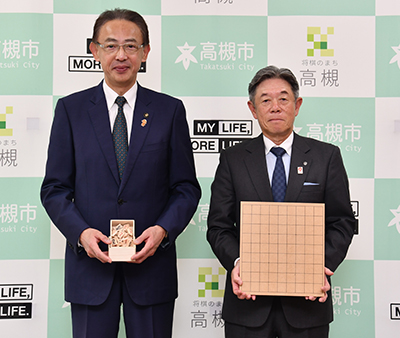 寄贈品を持つ間島社長と濱田市長