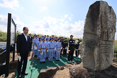 洪水記念碑の要約文を読み上げる職員たち
